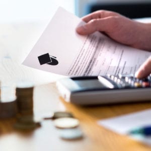 Man counting college savings fund, tuition fee or student loan with calculator. Education price and expenses concept. Money and papers on table. Calculating budget and planning finance.