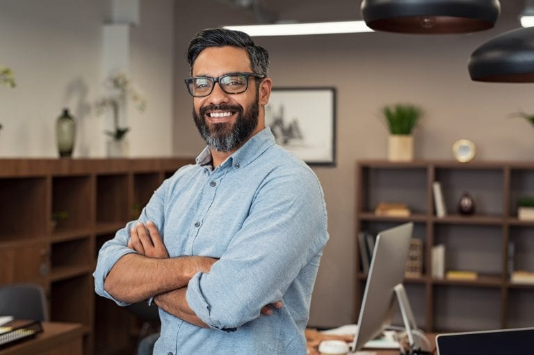 photo of man with beard and eyeglasses feeling confident at office. Successful middle eastern business man smiling in a creative office.