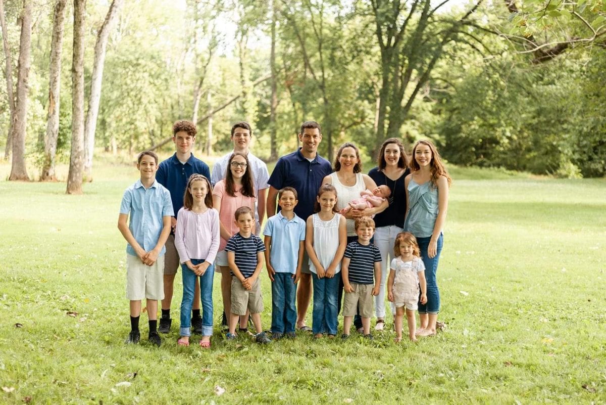 Burton Family of 15 poses in front of the camera together for family photo.