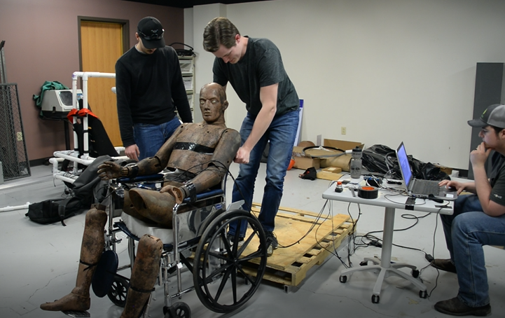 Students examine the test dummy in a wheelchair 