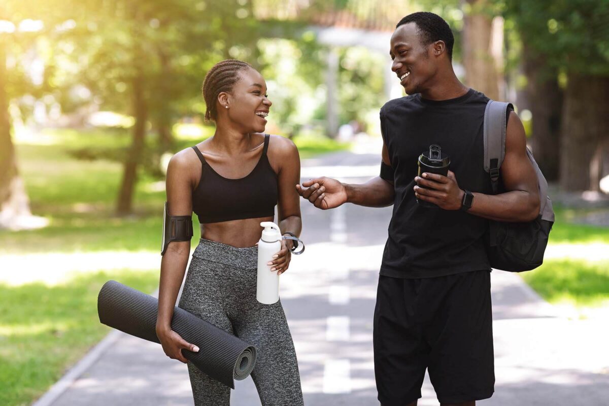 Young man and woman in workout clothes chatting outdoors.