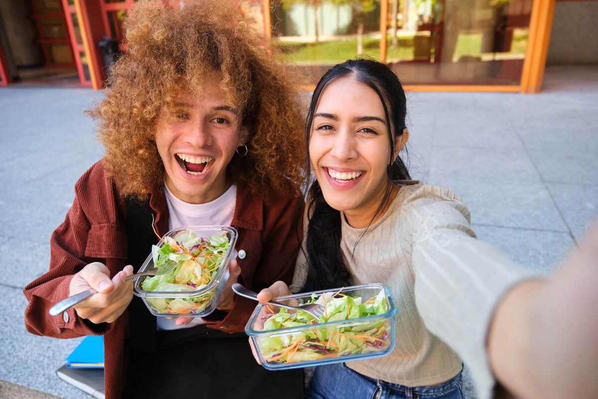 Two happy college students eating salads.