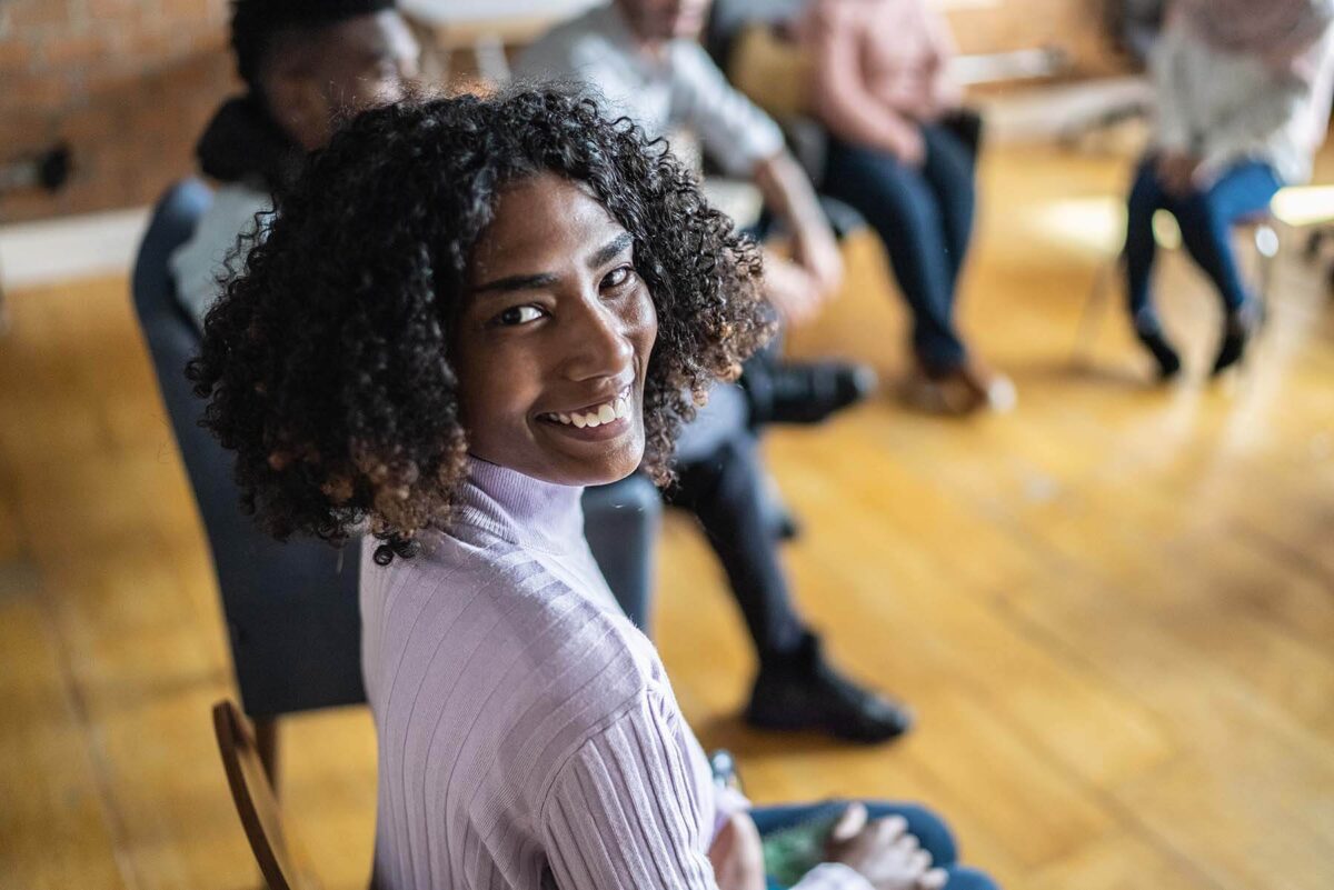Woman in group therapy smiling at the camera