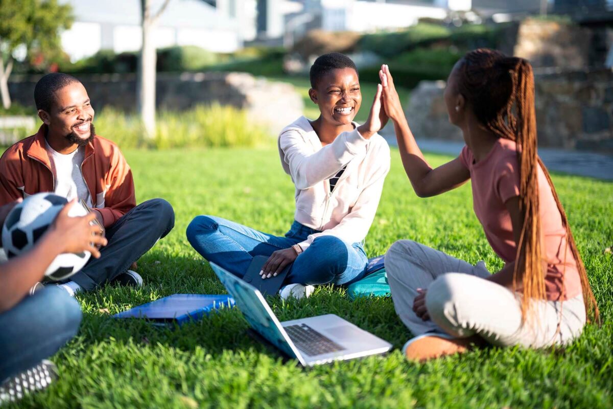 Two smiling women sitting on grass