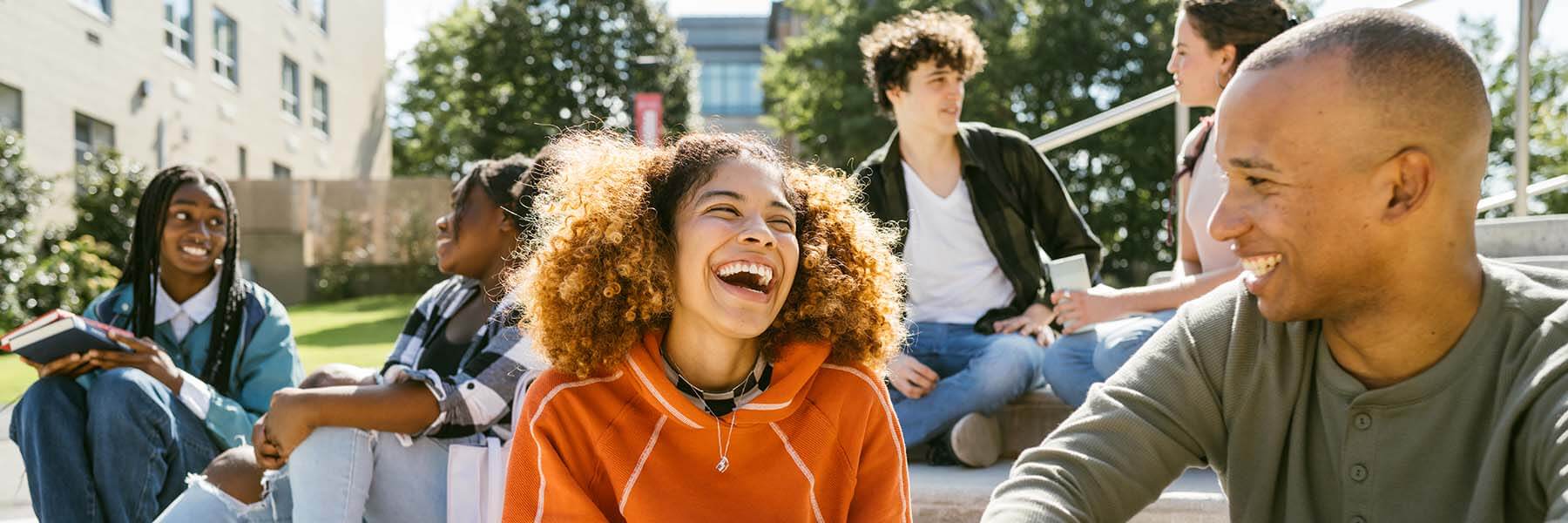 Laughing students sitting on steps outside