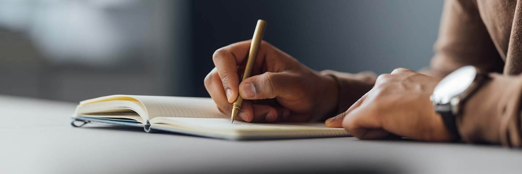 Closeup of a person writing in a notebook