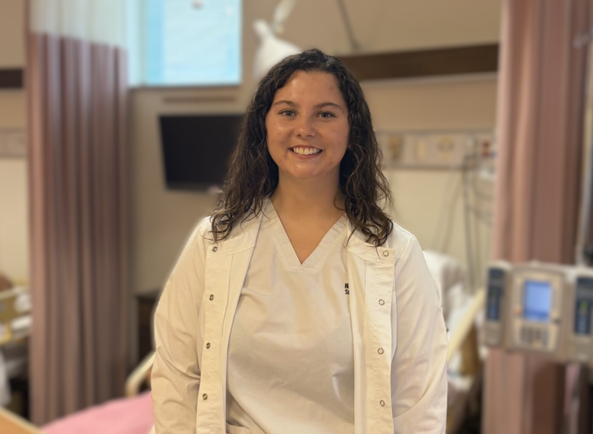 picture of student Brynnae Ables standing in the nursing classroom in his nursing uniform
