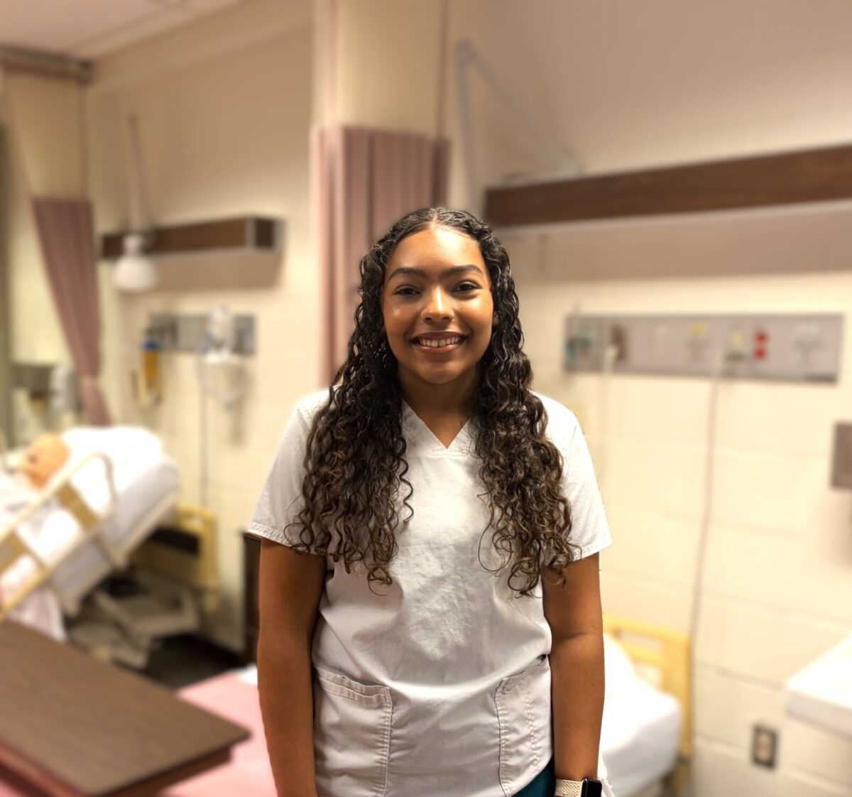 picture of student Shaya Montgomery standing in the nursing classroom in his nursing uniform