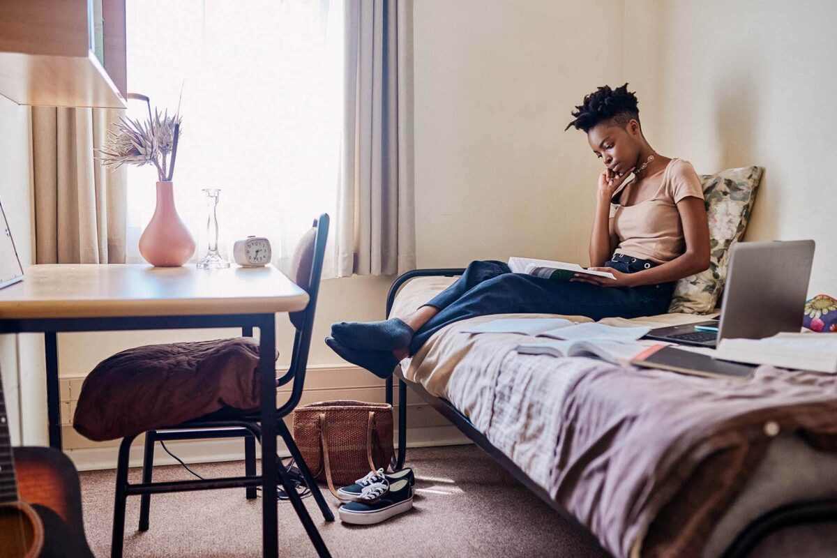 Young woman reading while sitting on her bed