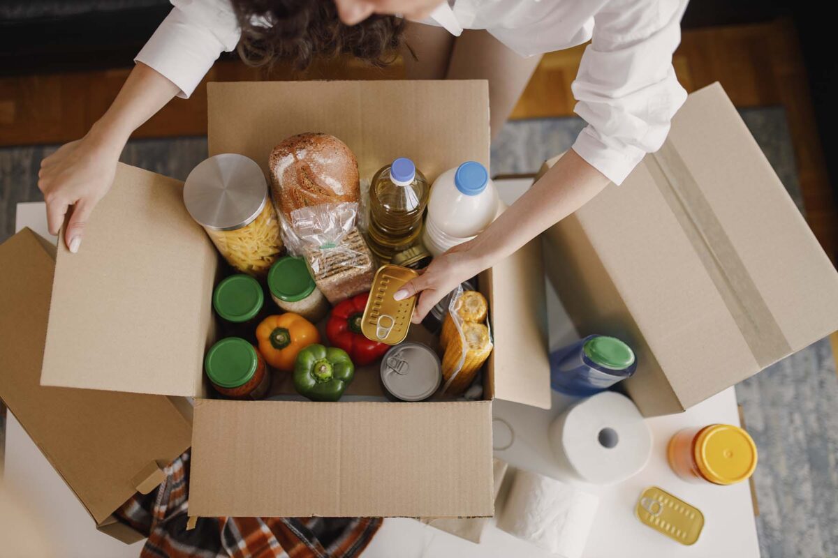 Person preparing a box of pantry food items