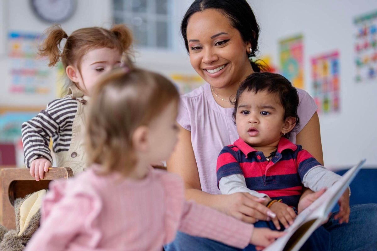 Childcare worker reads to three children