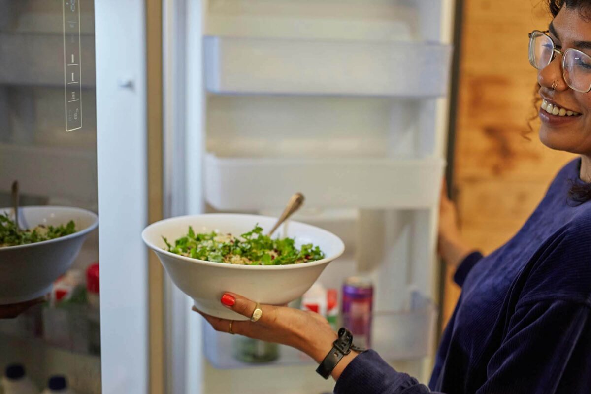 Woman getting a bowl of salad out of the refrigerator