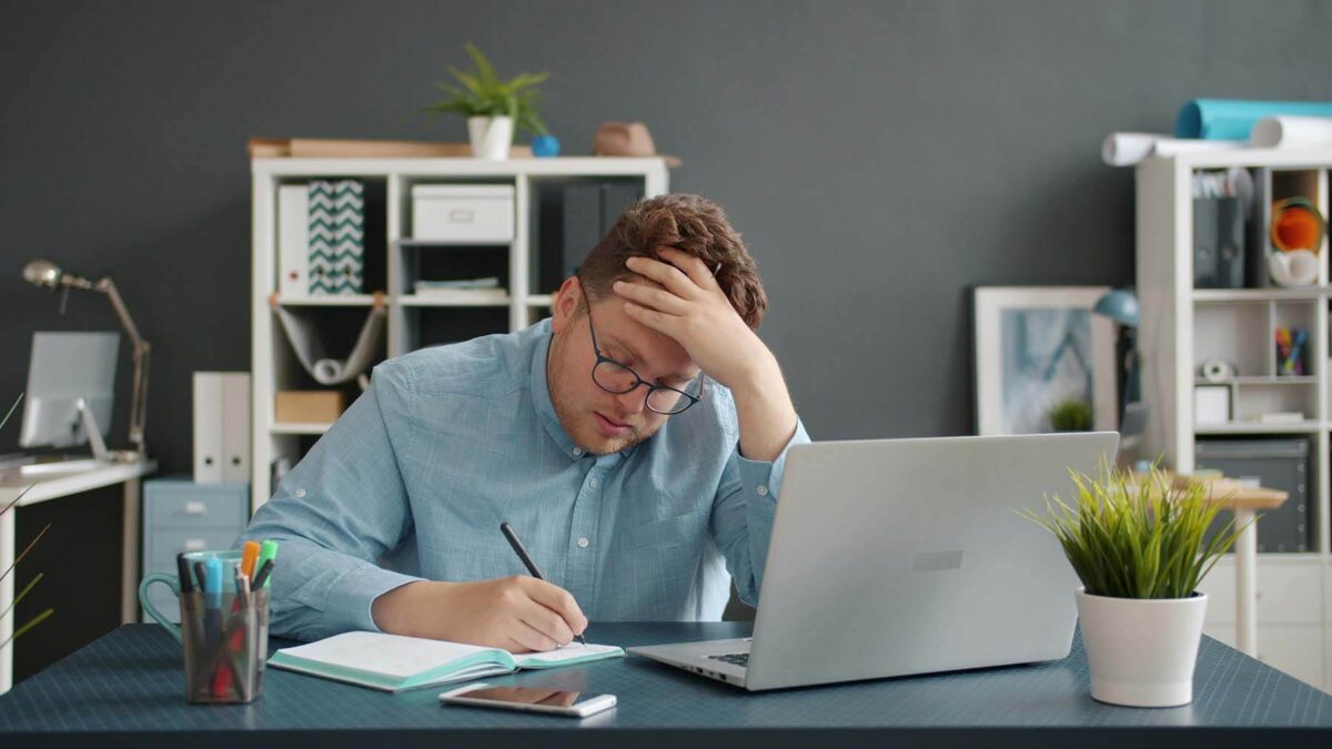 Stressed man writing at a desk
